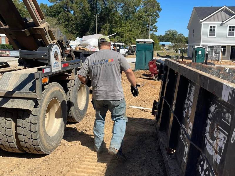The AMC Waste Services crew setting a roll-off dumpster in place