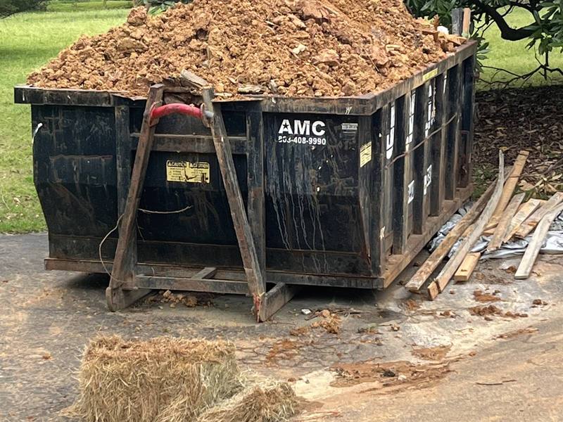 A roll-off dumpster loaded with dirt, ready for pickup