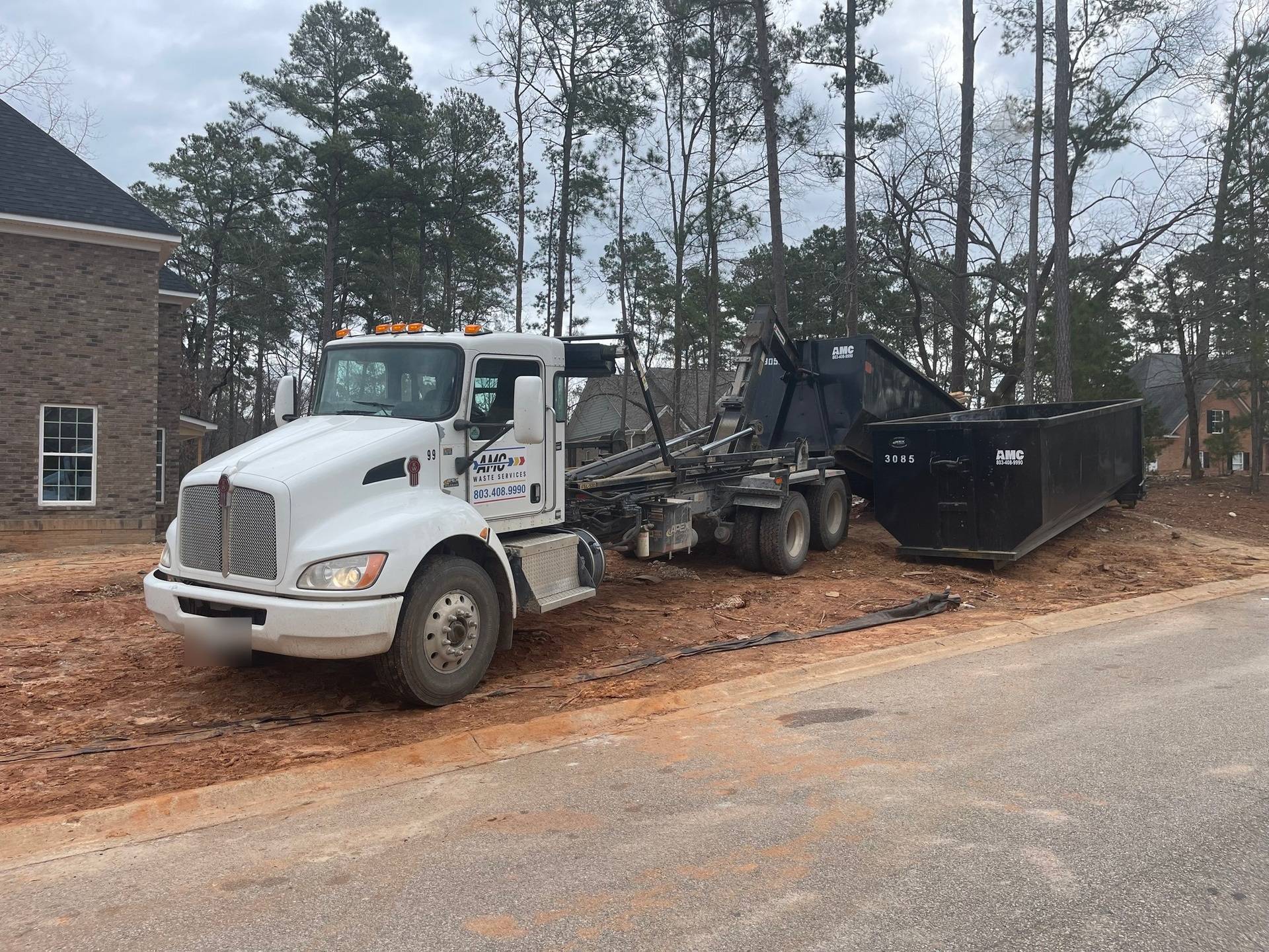 An AMC Waste Services truck delivering a dumpster to a new build in Chapin, Lexington County, SC