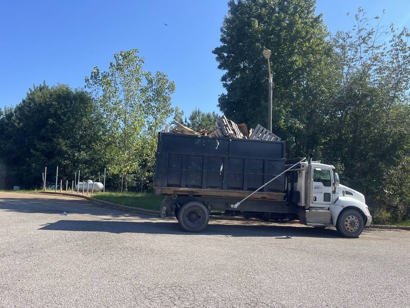An AMC truck hauling a loaded dumpster away from a cleanout