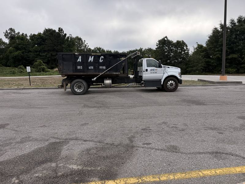 An AMC Waste Services roll-off truck hauling a dumpster near Lugoff, SC