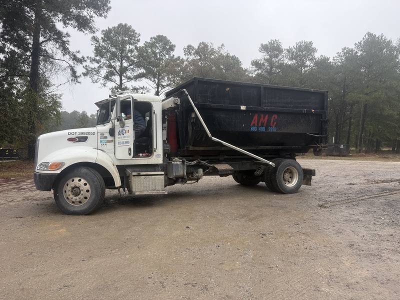 An AMC Waste Services truck rolling a dumpster off at a job in Columbia, Richland County, SC