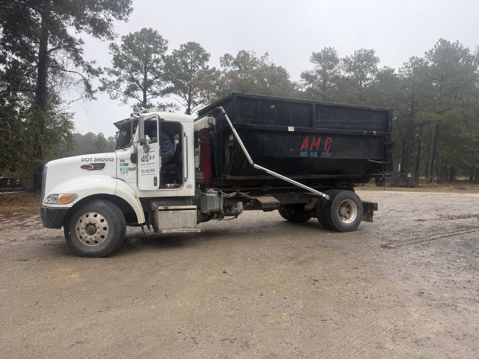 An AMC Waste Services truck rolling a dumpster off at a job in Columbia, Richland County, SC