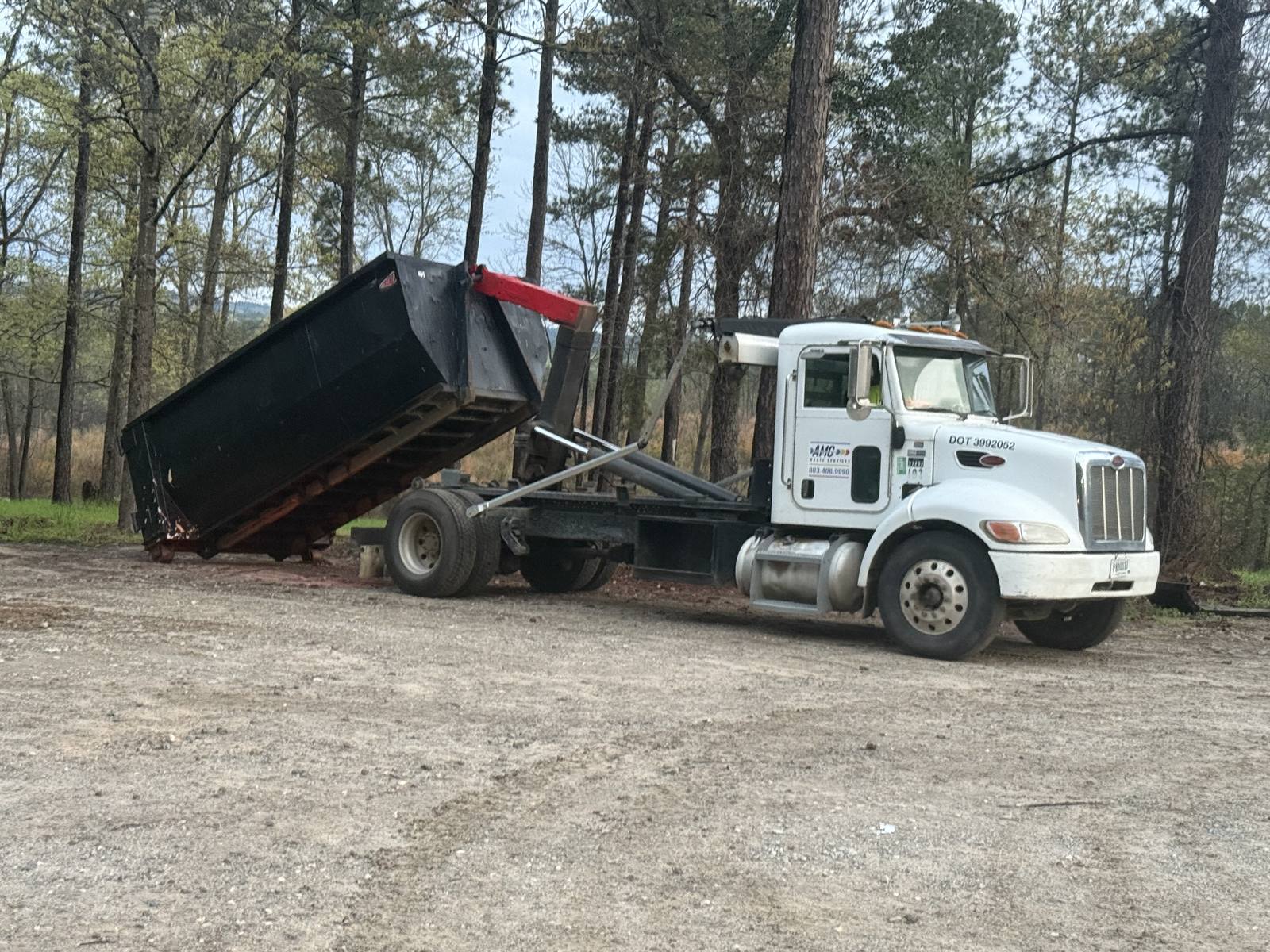 An AMC Waste Services truck tipping a dumpster off at a job in Greenville, Greenville County, SC