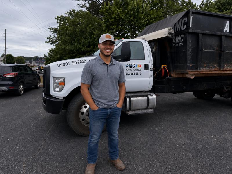 Zack, owner of AMC Waste Services, in front of one of his roll-off trucks